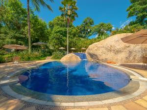 a pool with a large rock and blue water at Hotel Real Villa Bella in Ilhabela