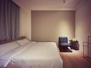 a bedroom with a white bed and a chair at 東海平行陸貳民宿English Friendly in Longjing
