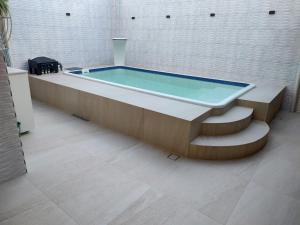 una piscina en una habitación con banco y bañera en Apartamento aconchegante, en Porto Seguro