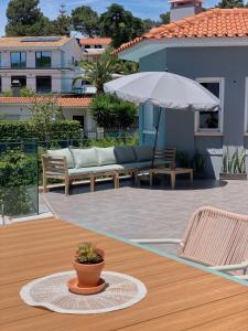 eine Terrasse mit einem Tisch, Stühlen und einem Sonnenschirm in der Unterkunft Luna House in Cascais