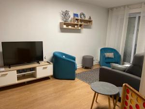 a living room with a television and two blue chairs at Appartement Face à la mer in Wimereux