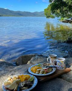 dos platos de comida en una mesa junto a un cuerpo de agua en Aluguel temporada, en Florianópolis