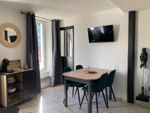 a dining room table with chairs and a television on a wall at Le Gaudissart 2 in Barcelonnette