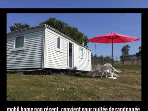 a red umbrella and two chairs and a tiny house at La Baronnerie in Saint-Marc-dʼOuilly
