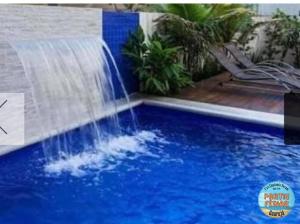 una cascada en una piscina de agua azul en Flat Capitania em Pitangueiras perto da praia en Guarujá