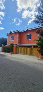 a orange house with a fence in front of it at El Rincón - El Jardín in Tunapuna