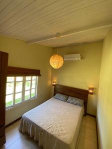 a bedroom with a bed and two windows at Morada dos Coqueiros in Garopaba