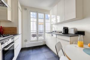 kuchnia z białymi szafkami, stołem i oknem w obiekcie Ideal 1 Bd Flat with Balcony - Paris 05 w Paryżu