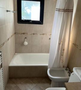 bagno con vasca, servizi igienici e finestra di Amplio departamento en zona céntrica a Junín