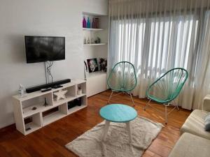 un soggiorno con 2 sedie e una TV di Amplio departamento en zona céntrica a Junín