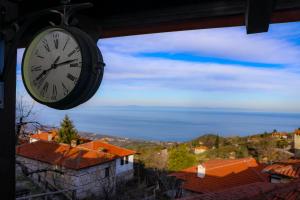 a clock hanging from a building with a view at Olympia Avra in Palaios Panteleimonas