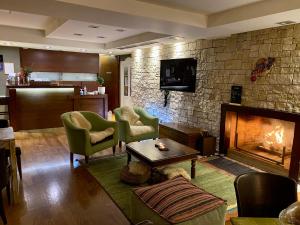 a living room with a fireplace with chairs and a table at Archontiko Zafeiropoulou in Kalavrita