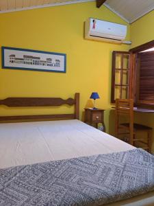 a bedroom with a bed and a yellow wall at Casa Amarela in Paraty +13 photos