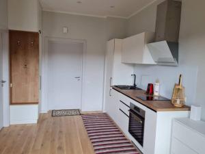 una cucina con mobili bianchi e pavimento in legno di Seaside Apartment "Sunrise" with terrace in Ķesterciems, Albatross a Ķesterciems