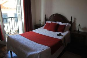 a bedroom with a bed with red pillows and a window at Hotel GORDON in Funchal