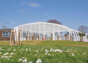 a large greenhouse in front of a field of flowers at Mersea Island Holiday Park in East Mersea