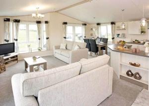 a living room with a white couch and a kitchen at Mersea Island Holiday Park in East Mersea