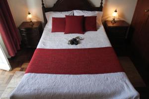 uma cama com um cobertor vermelho e branco e almofadas vermelhas em Hotel GORDON em Funchal