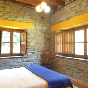 1 dormitorio con 1 cama en una pared de piedra en Valles del Narcea, Apartamentos Rurales, en Cangas del Narcea