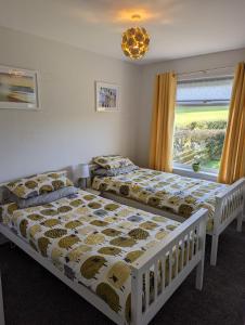 2 bedden in een slaapkamer met een raam bij Rural Cosy Three Bedroom Cottage in Girvan