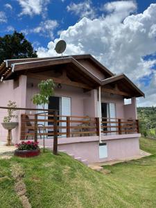 a small pink house with a wooden railing at Chácara Jerusalém in Lindóia