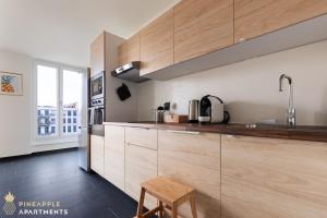 een keuken met houten kasten en een houten kruk bij Pineapple Apartments Dresden Altstadt IV - 91 qm - 1x free parking in Dresden