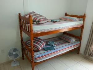 a wooden bunk bed with striped pillows and a fan at Way Up Hostel in Florianópolis