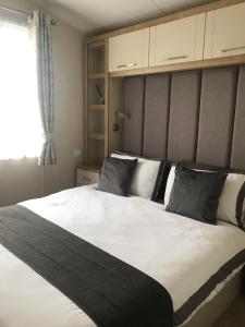 een slaapkamer met een groot wit bed met zwarte kussens bij The Cockle Shell Caravan, Seaview Holiday Park, Whitstable in Whitstable