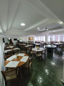 uma sala de jantar com mesas e cadeiras e uma sala cheia de mesas em Garanhuns Palace Hotel em Garanhuns