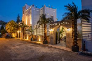 a hotel with palm trees in front of a building at Noa Suite Hotel Only Adult in Bodrum City
