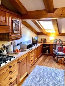 a large kitchen with wooden cabinets and a blue rug at Mansardina Mery Cortina in Cojana