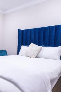 a large bed with a blue headboard and white pillows at Chic Guest House & Solar system free from load shedding in Germiston