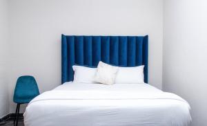 a bed with a blue headboard and a blue chair at Chic Guest House & Solar system free from load shedding in Germiston