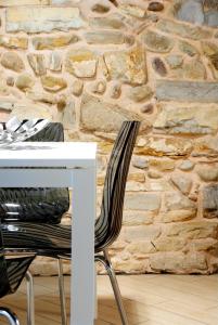 ベルガモにあるB&B Home Sweet Homeの石壁の横に白いテーブルと椅子