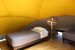 a yellow room with a bed and a fan at RetroDOMOS in Coinco