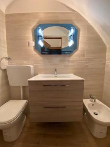 ein Badezimmer mit einem WC, einem Waschbecken und einem Spiegel in der Unterkunft 1931 Apartments - Borgo Antico - Gargano in Ischitella