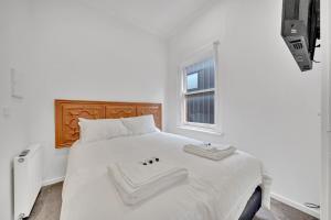 a white bed with two towels on top of it at Grosvenor 3121 Richmond in Melbourne