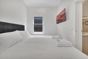 a white bedroom with a large white bed and a window at Grosvenor 3121 Richmond in Melbourne