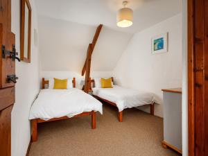 Duas camas num quarto com paredes brancas e almofadas amarelas em Little Leighs em Launceston