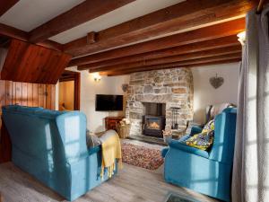 a living room with two blue chairs and a stone fireplace at Pond Meadow in Launceston