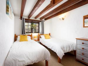two beds in a room with white sheets and yellow pillows at Pond Meadow in Launceston