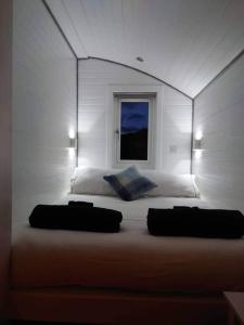 a bedroom with a bed with two pillows and a window at Loch Shiel Luxury Pod in Acharacle
