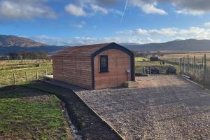 a small building in the middle of a field at Loch Shiel Luxury Pod in Acharacle