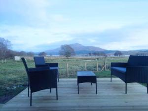 a group of chairs and a table with a view of a field at Loch Shiel Luxury Pod in Acharacle