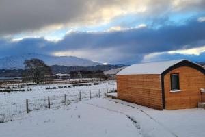 Loch Shiel Luxury Pod في أكاريكيل: مبنى من الطوب صغير في حقل مغطى بالثلج
