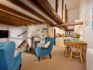 a living room with blue chairs and a stone fireplace at Ash Cottage in Launceston