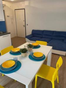 a white table with yellow chairs and a blue couch at Appartamento Grado Pineta Holidays in Grado