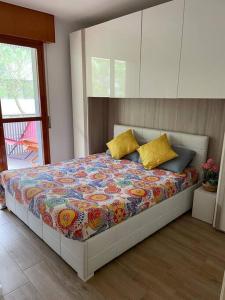 Appartamento Grado Pineta Holidays في غرادو: غرفة نوم بسرير ولحاف ملون ومخدات صفراء