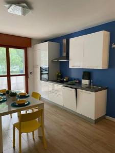 a kitchen with white cabinets and a table with chairs at Appartamento Grado Pineta Holidays in Grado