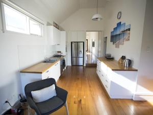 a kitchen with white cabinets and a chair in it at GALWAY COTTAGE in Queenscliff